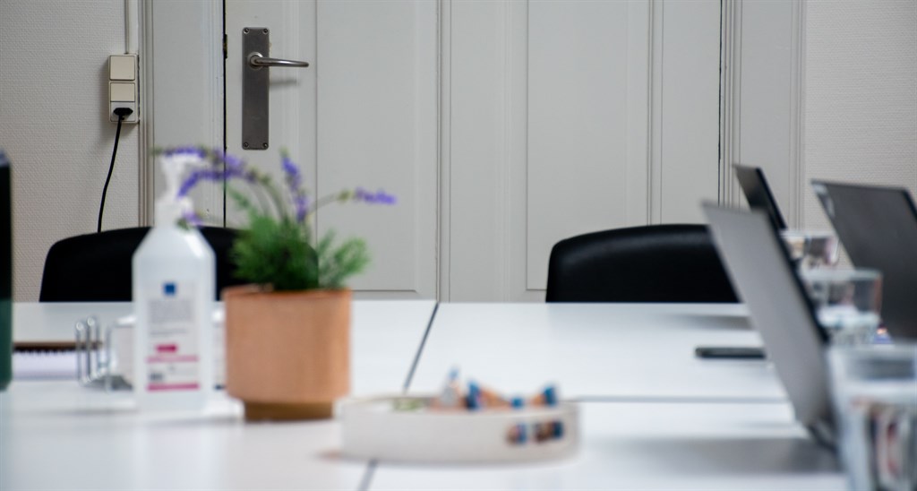 Billede af mødebord med computere og blomst